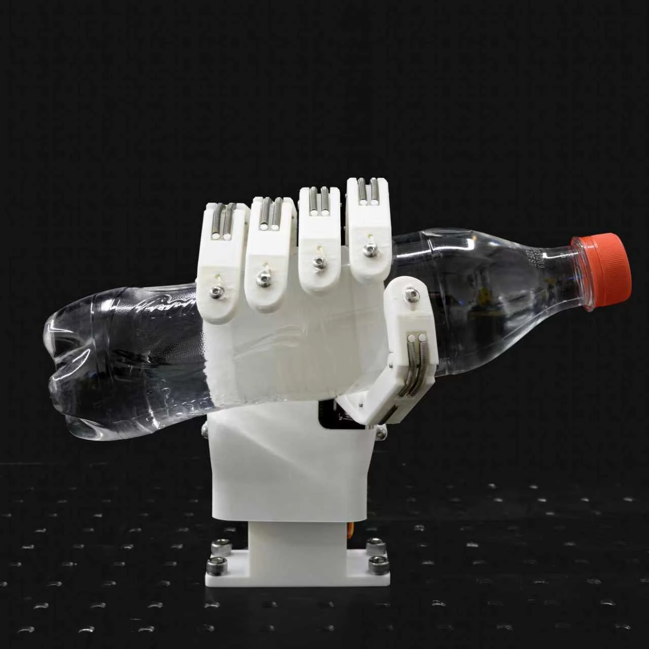 A white prosthetic hand prototype grasping a clear plastic bottle